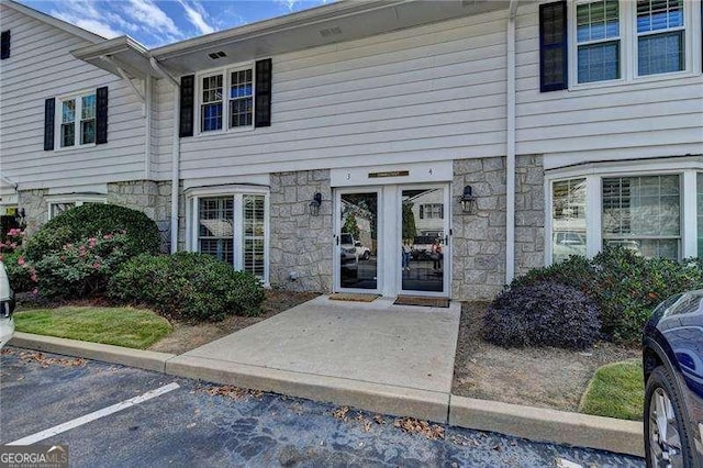 property entrance with stone siding and uncovered parking