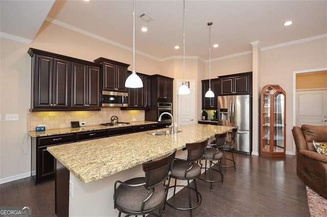 kitchen with dark wood-style floors, a sink, stainless steel appliances, a kitchen breakfast bar, and backsplash