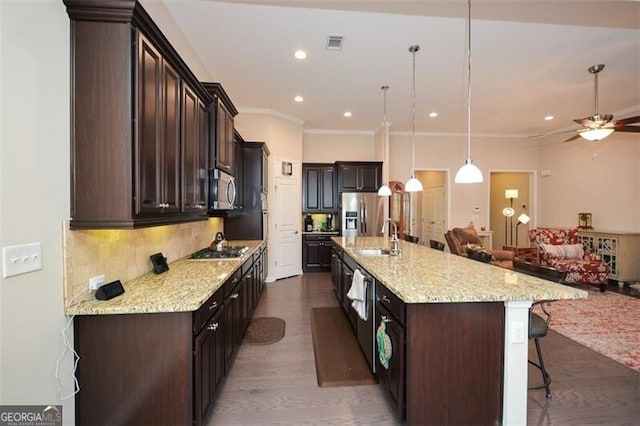 kitchen featuring tasteful backsplash, dark brown cabinetry, open floor plan, a breakfast bar, and stainless steel appliances