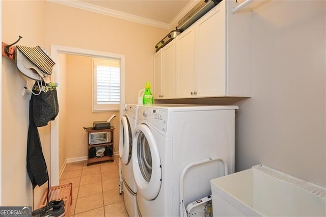 washroom featuring ornamental molding, cabinet space, light tile patterned floors, baseboards, and washing machine and clothes dryer