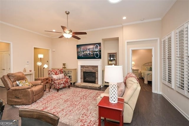 living area with dark wood-style floors, a stone fireplace, a ceiling fan, and ornamental molding