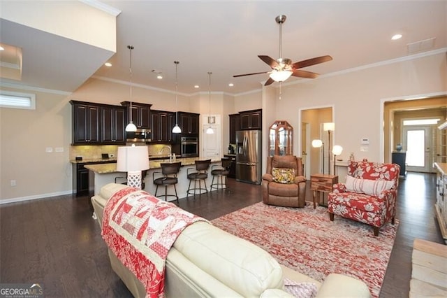 living area featuring dark wood finished floors, a ceiling fan, and crown molding