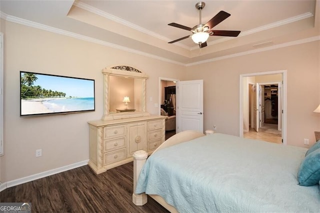 bedroom featuring baseboards, a raised ceiling, dark wood-style floors, and crown molding