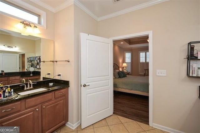 ensuite bathroom with tile patterned floors, ensuite bathroom, crown molding, baseboards, and vanity