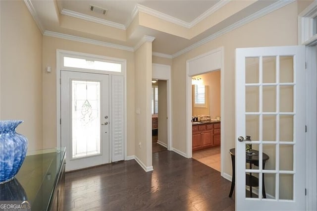 foyer entrance with dark wood-type flooring, baseboards, visible vents, and ornamental molding