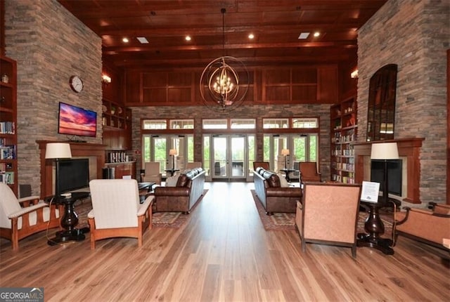 living area with a chandelier, wood ceiling, a stone fireplace, a high ceiling, and wood finished floors