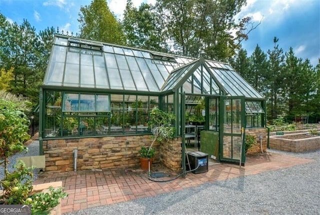 view of patio with a greenhouse and an outdoor structure