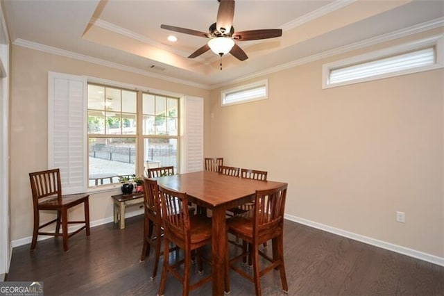 dining room featuring a raised ceiling, crown molding, dark wood-style floors, and baseboards