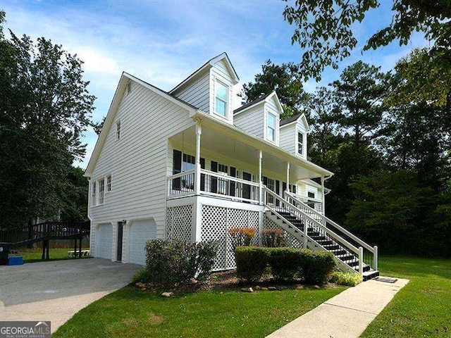 new england style home with a front lawn, stairway, a porch, a garage, and driveway