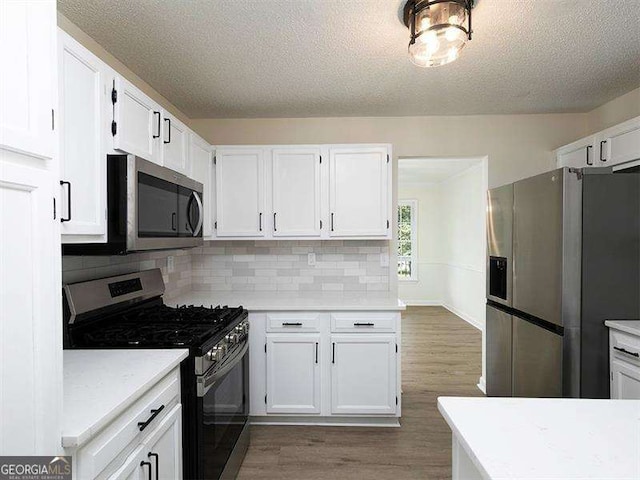 kitchen featuring appliances with stainless steel finishes, white cabinets, and light countertops