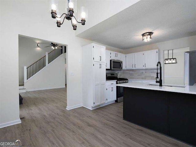 kitchen with dark wood-type flooring, a textured ceiling, backsplash, stainless steel appliances, and light countertops