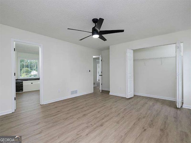 unfurnished bedroom with visible vents, a textured ceiling, baseboards, and wood finished floors