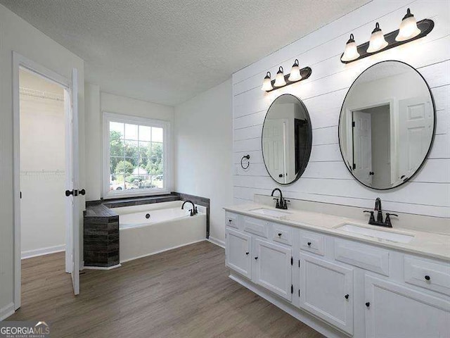 bathroom featuring a textured ceiling, wood finished floors, and a sink