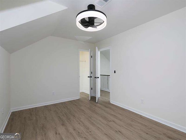 bonus room with lofted ceiling, wood finished floors, baseboards, and visible vents