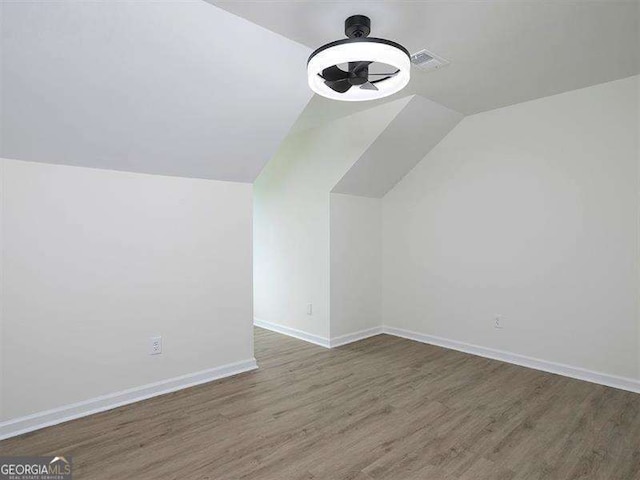 additional living space with a ceiling fan, wood finished floors, visible vents, baseboards, and lofted ceiling