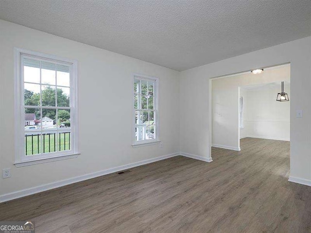 spare room with a textured ceiling, dark wood-type flooring, and baseboards