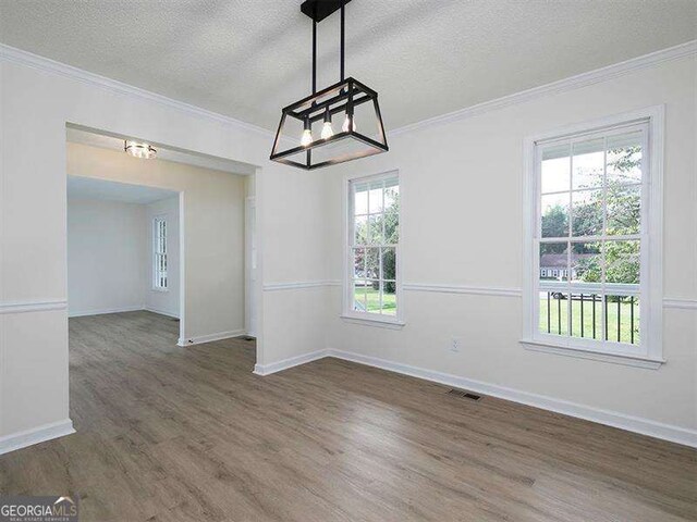 unfurnished dining area featuring crown molding, wood finished floors, and visible vents