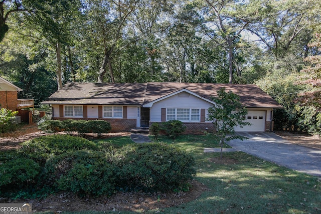 single story home with driveway, brick siding, an attached garage, and a front lawn