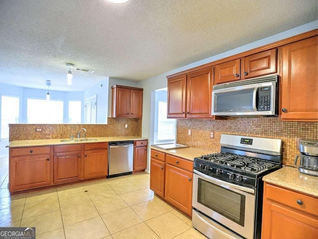 kitchen with light tile patterned floors, a peninsula, a sink, decorative backsplash, and appliances with stainless steel finishes