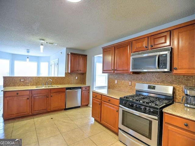 kitchen with brown cabinetry, backsplash, appliances with stainless steel finishes, and a sink