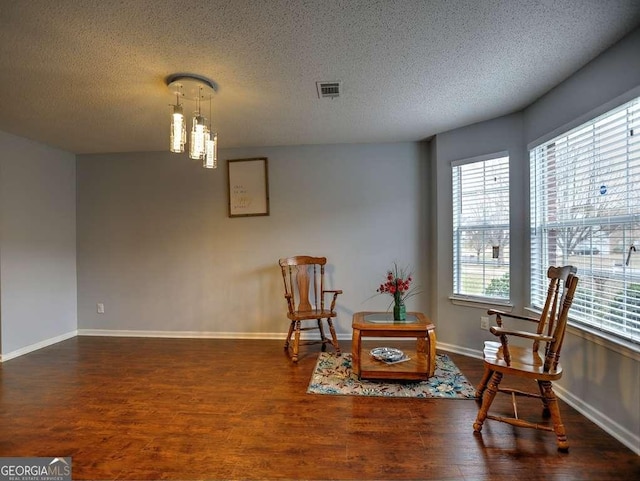 sitting room with wood finished floors, baseboards, and a textured ceiling