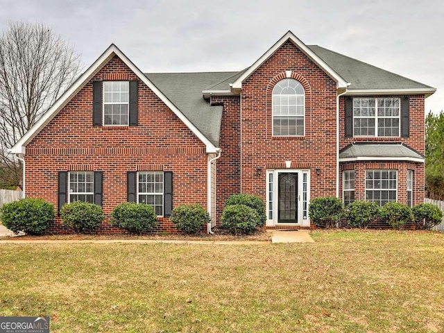 view of front of property with brick siding, a front lawn, and a shingled roof