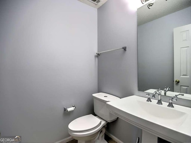 half bath featuring a sink, baseboards, and toilet