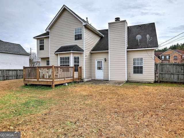 back of house with a lawn, a chimney, a deck, and fence