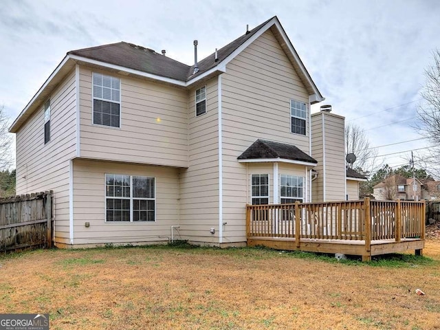 rear view of house with a shingled roof, fence, a chimney, a deck, and a yard