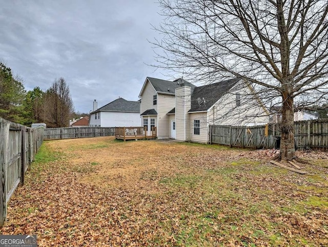 back of property with a yard, a deck, and a fenced backyard