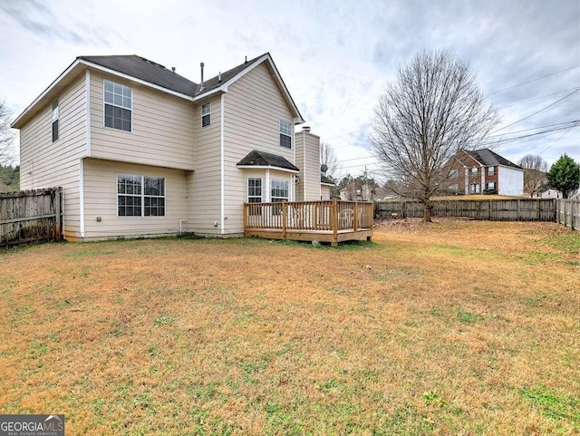 rear view of house with a deck, a lawn, and a fenced backyard