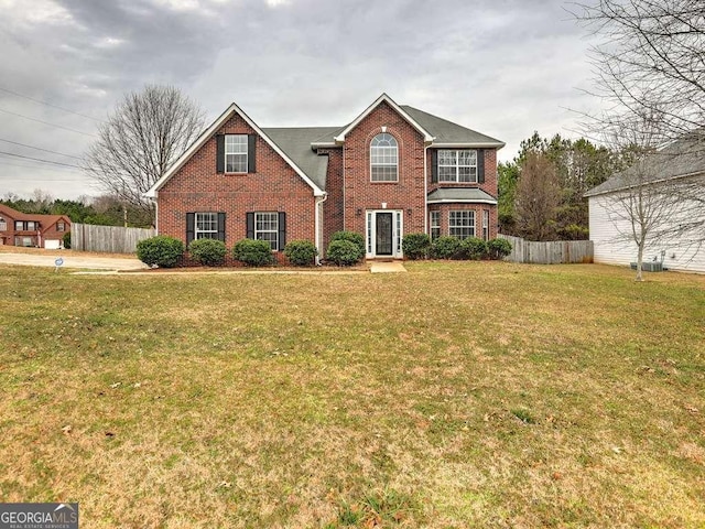 view of front of property with a front lawn, fence, and brick siding