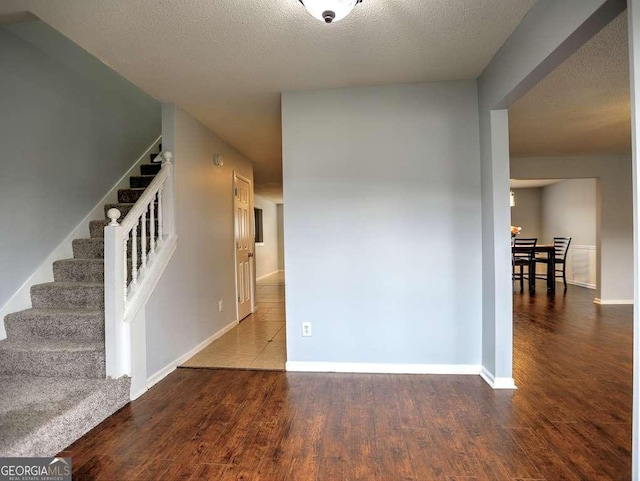 interior space with a textured ceiling, stairs, baseboards, and wood finished floors