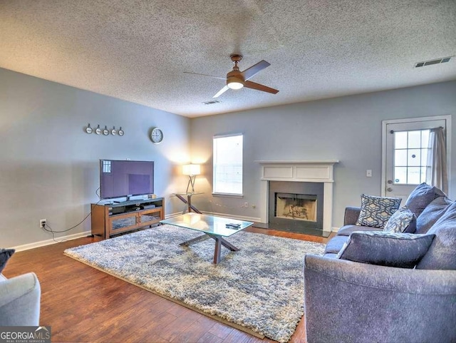 living room with a fireplace with flush hearth, wood finished floors, a wealth of natural light, and ceiling fan