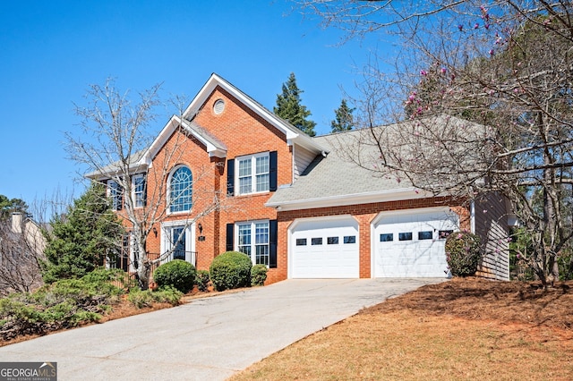 colonial inspired home featuring brick siding, driveway, a garage, and roof with shingles