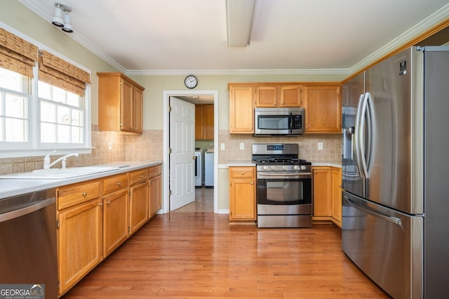 kitchen with light countertops, independent washer and dryer, appliances with stainless steel finishes, and a sink