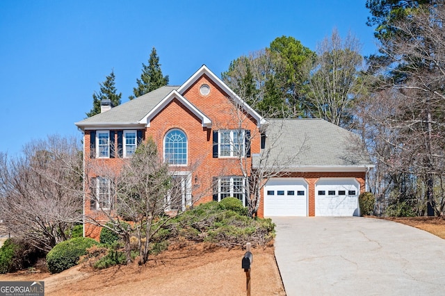 colonial home featuring a garage, brick siding, a chimney, and driveway