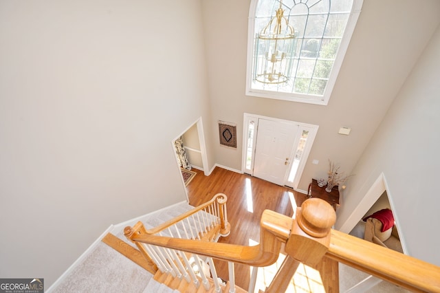 entryway with a high ceiling, a notable chandelier, wood finished floors, and baseboards