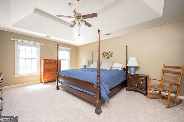 bedroom with visible vents, light carpet, a raised ceiling, ornamental molding, and baseboards