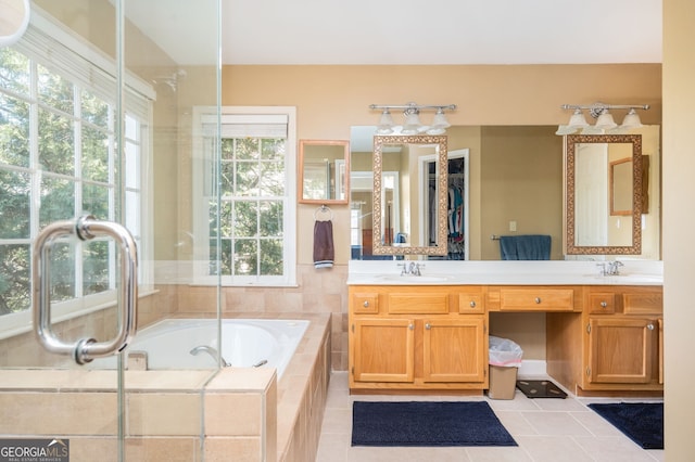 full bath featuring a bath, tile patterned flooring, double vanity, and a sink