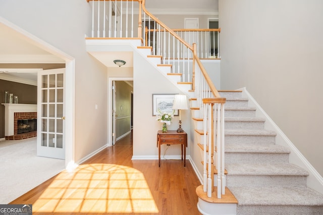 staircase with baseboards, wood finished floors, ornamental molding, and a fireplace