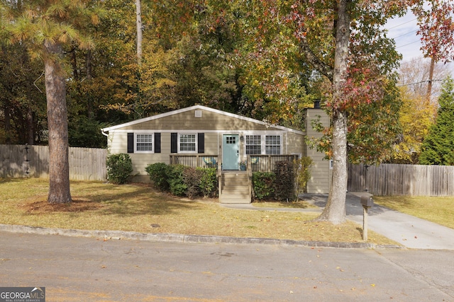 view of front of property with a porch, a front yard, and fence