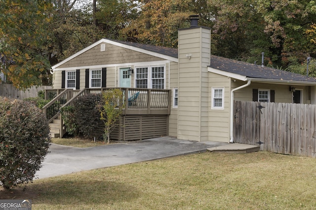 view of front of home featuring a shingled roof, a chimney, a front yard, and fence