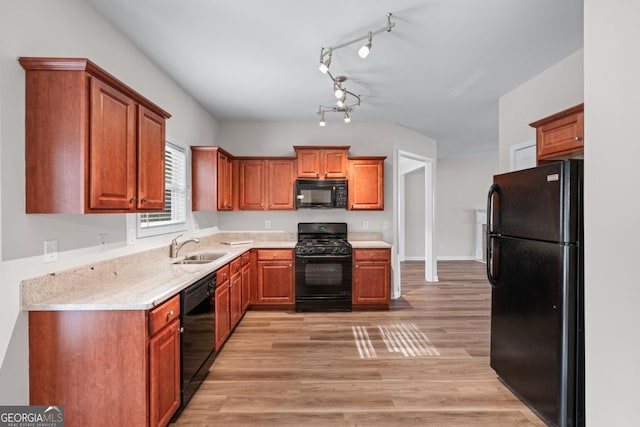 kitchen with black appliances, light wood-style flooring, light countertops, and a sink