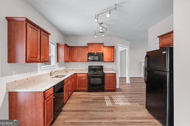 kitchen with black appliances, light countertops, light wood-style floors, and a sink