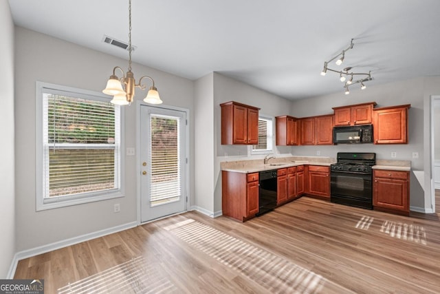 kitchen featuring visible vents, black appliances, a sink, light countertops, and a chandelier