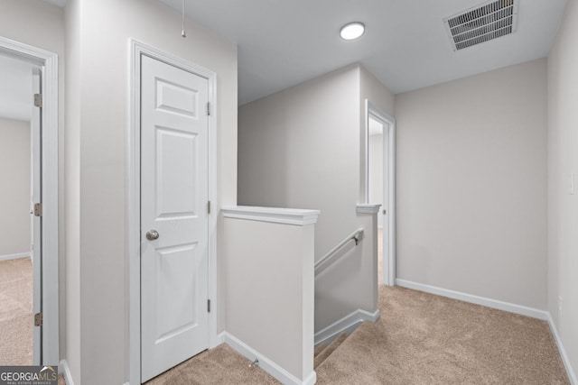 corridor with an upstairs landing, visible vents, carpet flooring, and baseboards