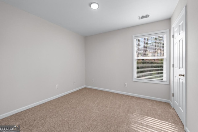 carpeted spare room with visible vents and baseboards