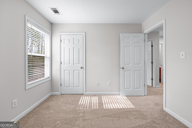 unfurnished bedroom featuring baseboards, carpet floors, and visible vents