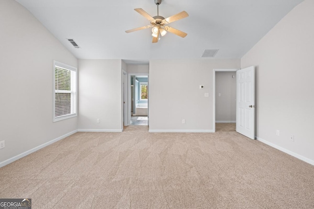 unfurnished bedroom featuring visible vents, lofted ceiling, light colored carpet, and baseboards